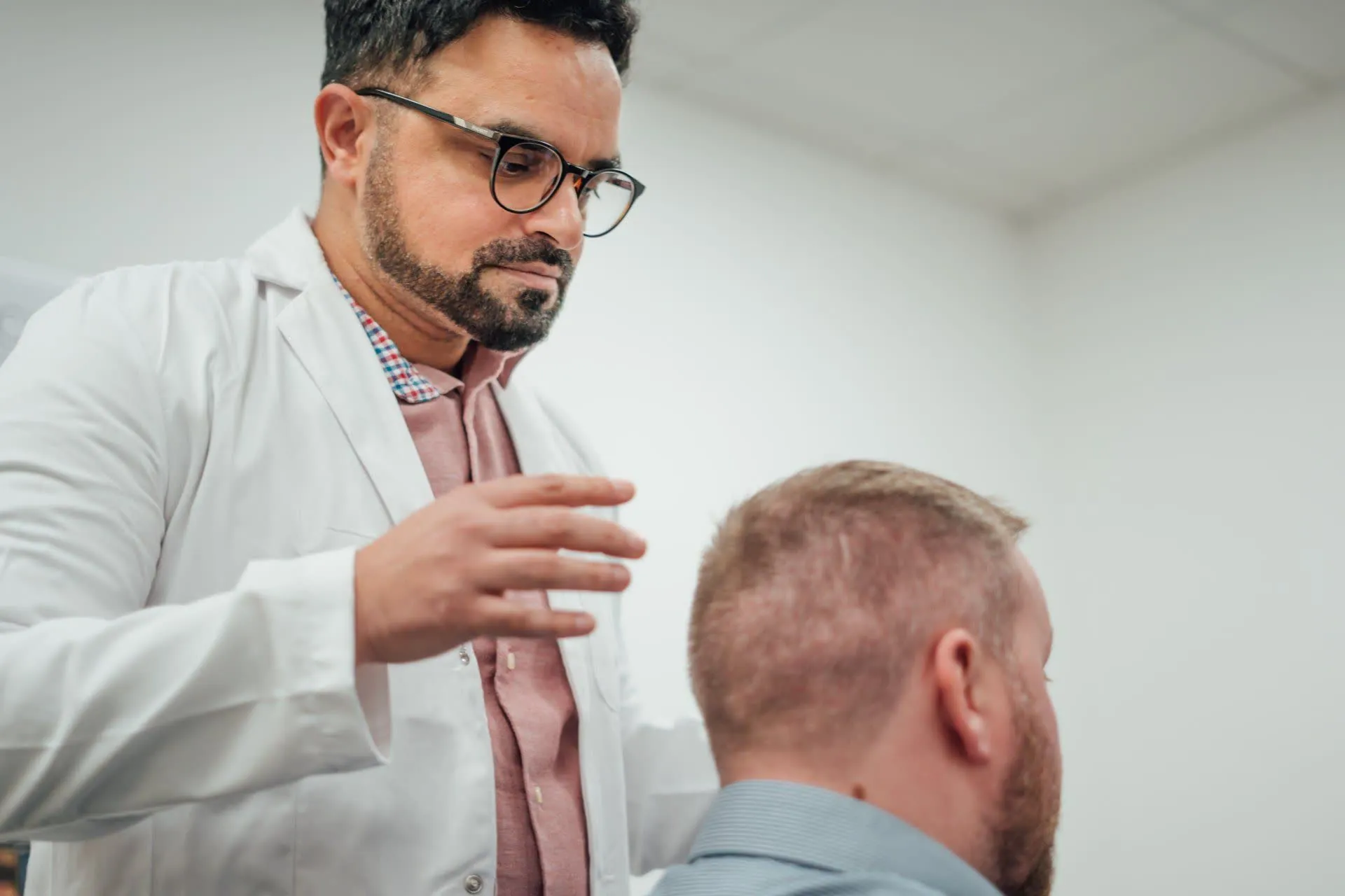 Dr Matee assessing a patient's hairline at a consultation